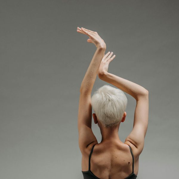 Person holding a balanced yoga pose against a minimal background.